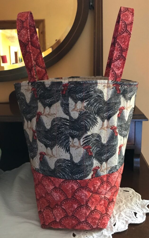Quilted tote bag with packed roosters on upper half and coordinating red patterned fabric on the lower half