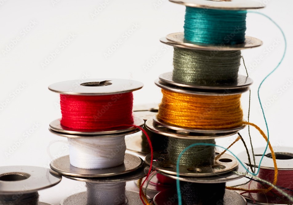A stack of sewing machine bobbins with thread