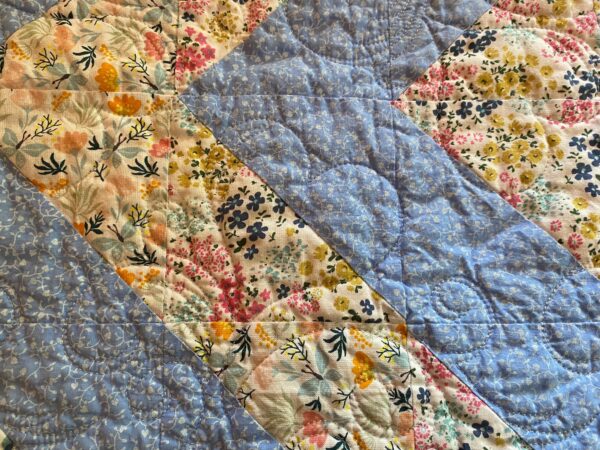 detailed look at a flowery blue baby quilt