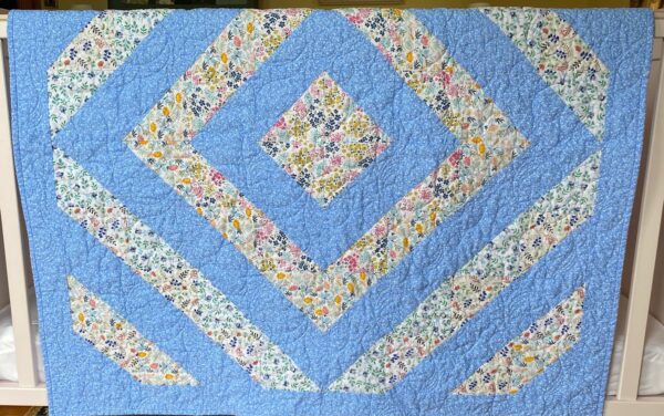 the geometric design of a blue flowery baby quilt