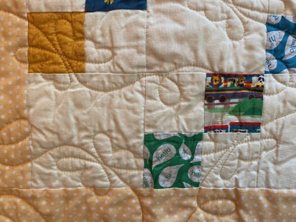 yellow baby quilt with images of small animals at play