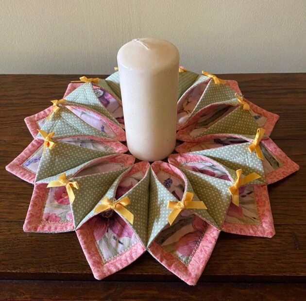 A fabric wreath for summer in pink, green and yellow featuring a candle in the centre