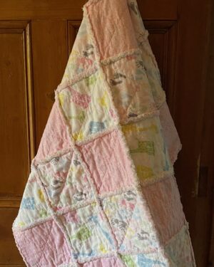 a baby rag quilt with colourful baby giraffes, hands and feet