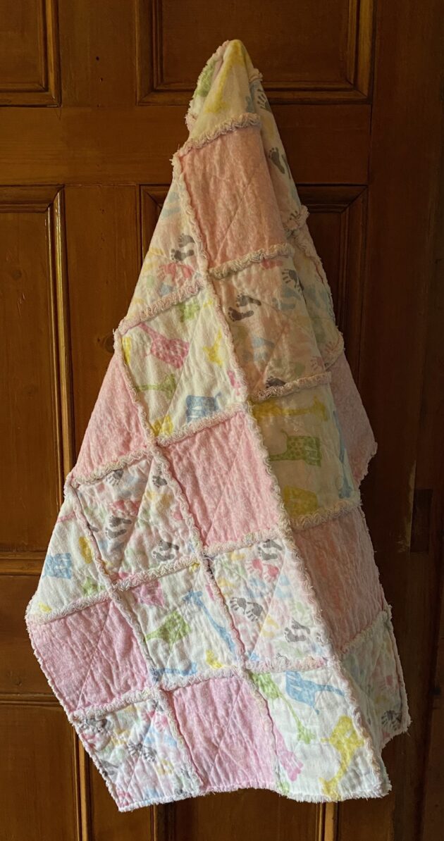 a baby rag quilt with colourful baby giraffes, hands and feet