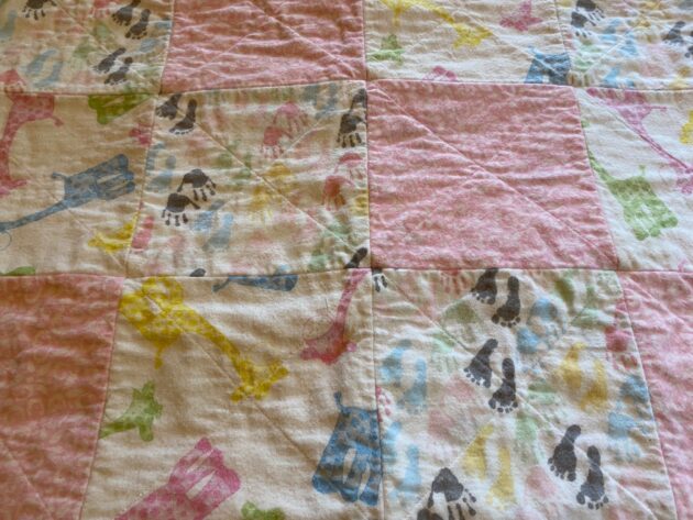 close up view of a a baby rag quilt with colourful baby giraffes, hands and feet