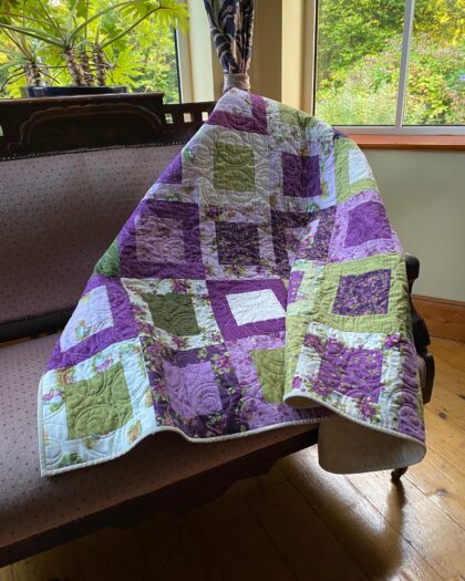 A beautiful throw quilt in lavenders and greens based on Anne of Green Gables