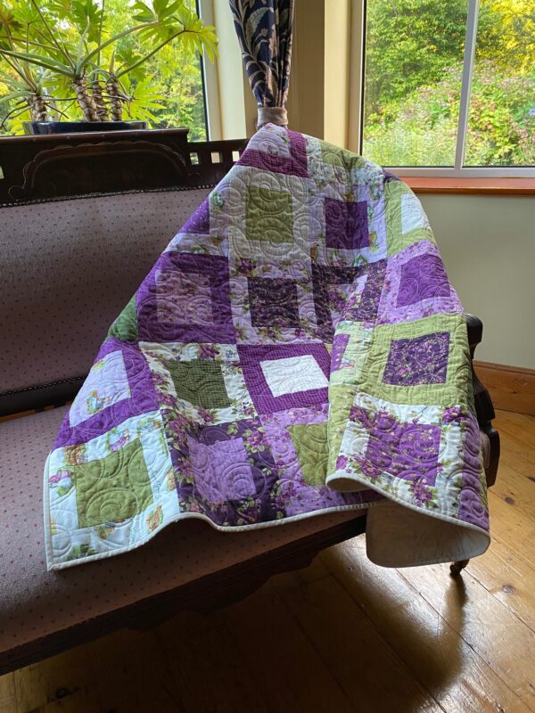 A beautiful throw quilt in lavenders and greens based on Anne of Green Gables