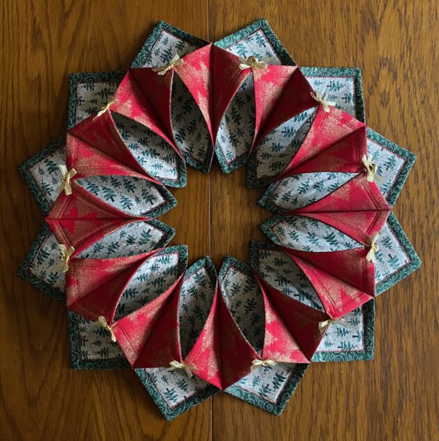 A fabric Christmas wreath in red, green, white and gold with gold metallic bows and bells