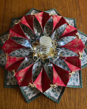 A candle, gold beads and LED lights are placed in the centre of a large fabric Christmas table wreath made with green, red and white cotton fabrics