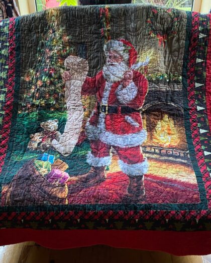 A Christmas throw quilt featuring Santa Claus checking his list