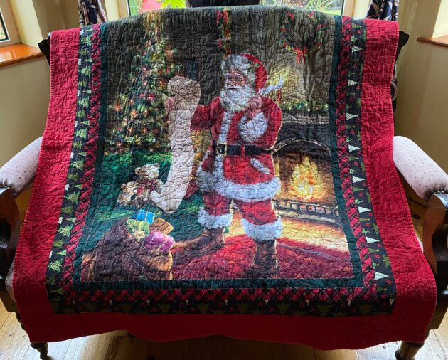 A Christmas throw quilt featuring Santa Claus checking his list