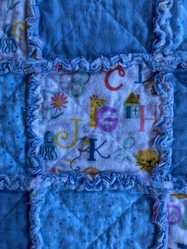 a close-up view of a blue rag quilt for a baby boy