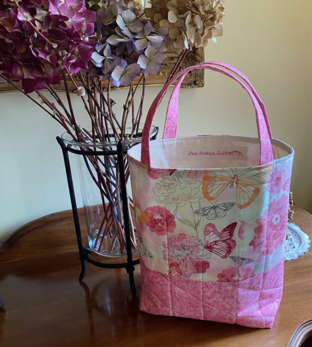 A lovely quilted tote bag made with a fabric full of butterflies and flowers