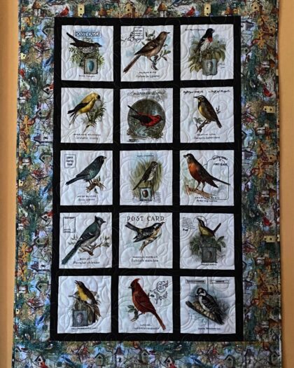 a quilted wall hanging depicting songbirds of North America