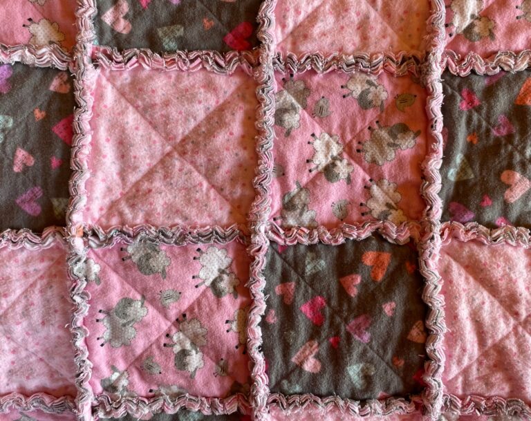 close-up view of a cotton flannel baby rag quilt featuring colourful hearts and baby lambs
