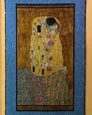 A quilted wall hanging of Klimt's "The Kiss" with a blue border