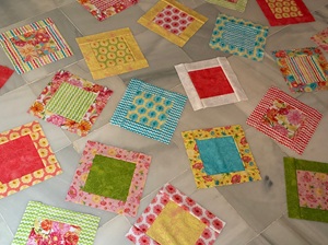 A group of colourful quilt blocks laid out on a marble floor