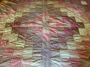 a hand-tied patchwork quilt in mauve and pink in the Trip Around the World pattern