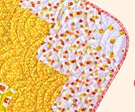 image of a rounded corner on a yellow, red and white quilt