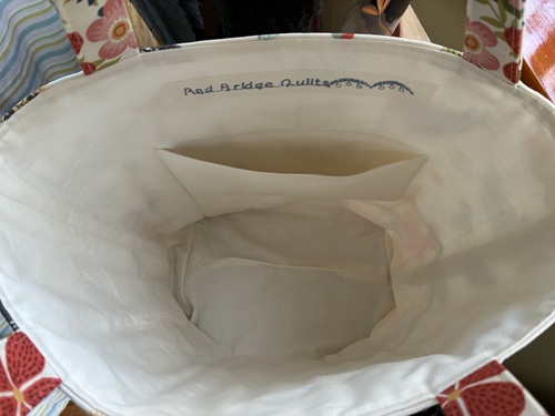 Interior view of a tote bag with a small inner pocket and light lining, seen from above.