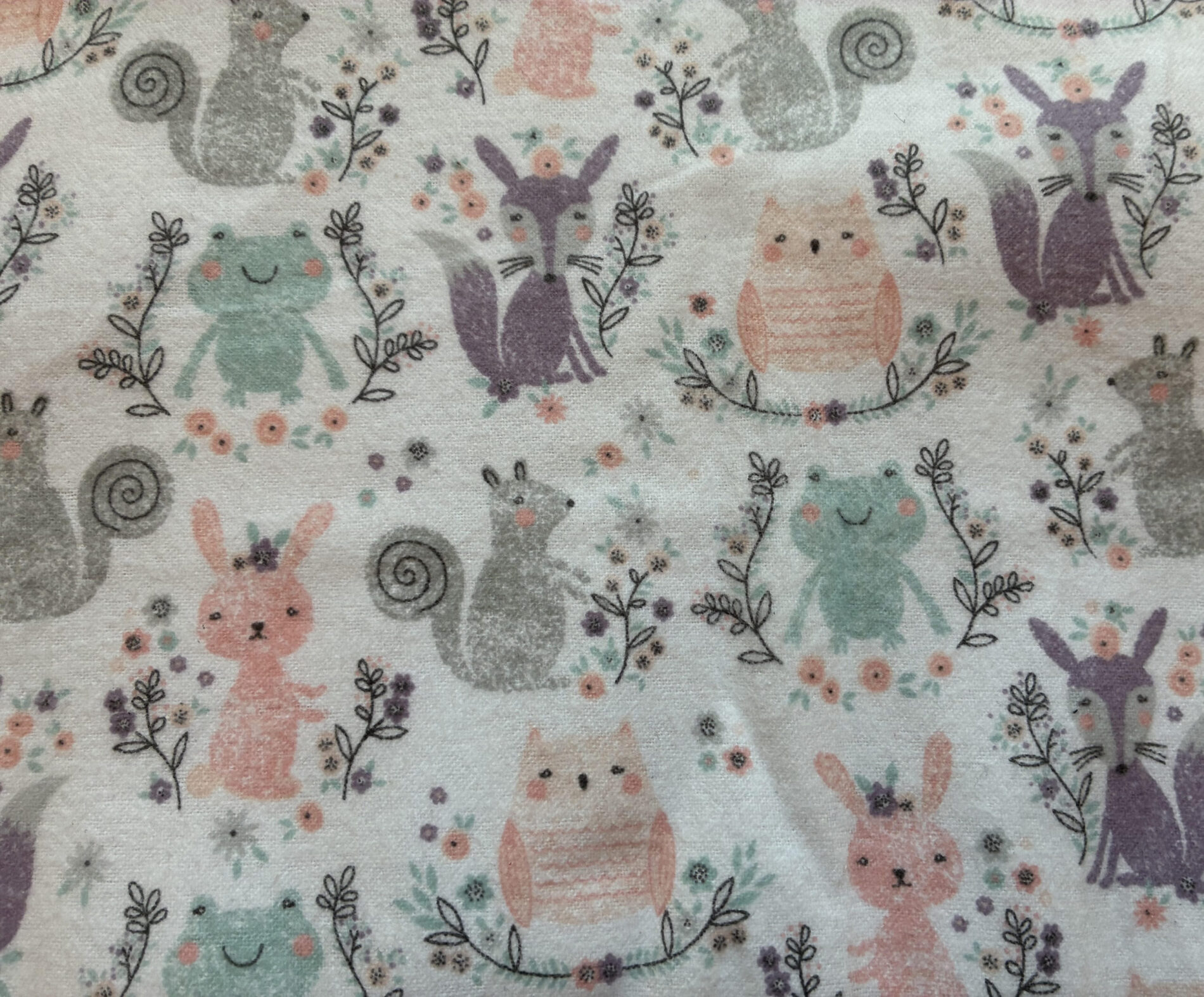 Pastel fabric pattern with cute animal shapes in pink, teal and purple among small flowers and vines.