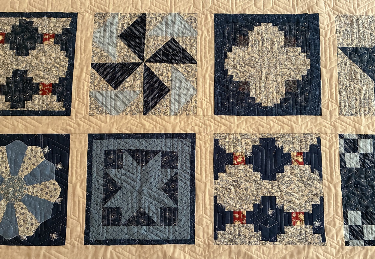 An example of a sampler quilt using several different patchwork block designs and quilted with a geometric pattern