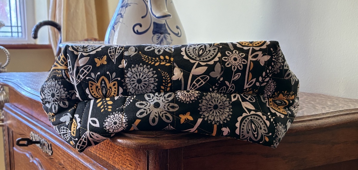 a view of the boxed bottom of a yellow, black and white tote bag resting on a window ledge